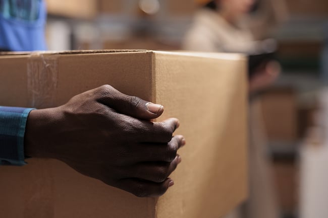 close up of man's hand carrying a box to be shipped