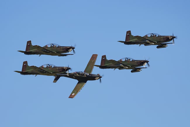 Five military aircraft in flight on a bright sunny day with blue skies.