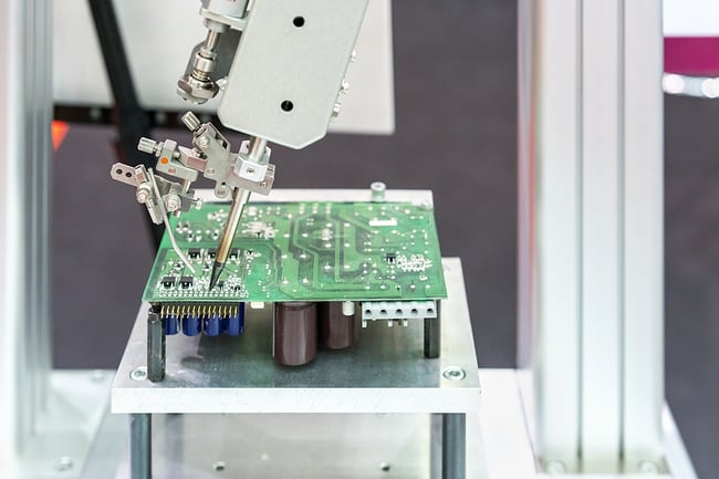 Close up of robotic arm in printed circuit board manufacturing. Green PCB.